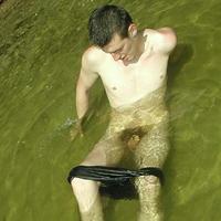 Young boy gets naked and plays in the stream.