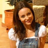 Beautiful brunette Carla enjoys the sun in a casual dungaree minidress, white crop top and bikini.