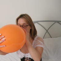 Wench in stockings blowing up balloons