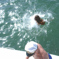 Cute little brunette swims back to the shore after a hard bang on boat