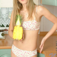 Long haired teen blonde posing and playing with toy fruit in the kitchen