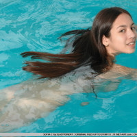 Long dark hair flows through water like a breeze as this pretty naked model swims.
