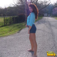 Ginger cheerleader teen poses by the road almost topless