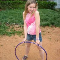 Uninhibited petite teen Kitty Kim playing hoola hoop outdoors